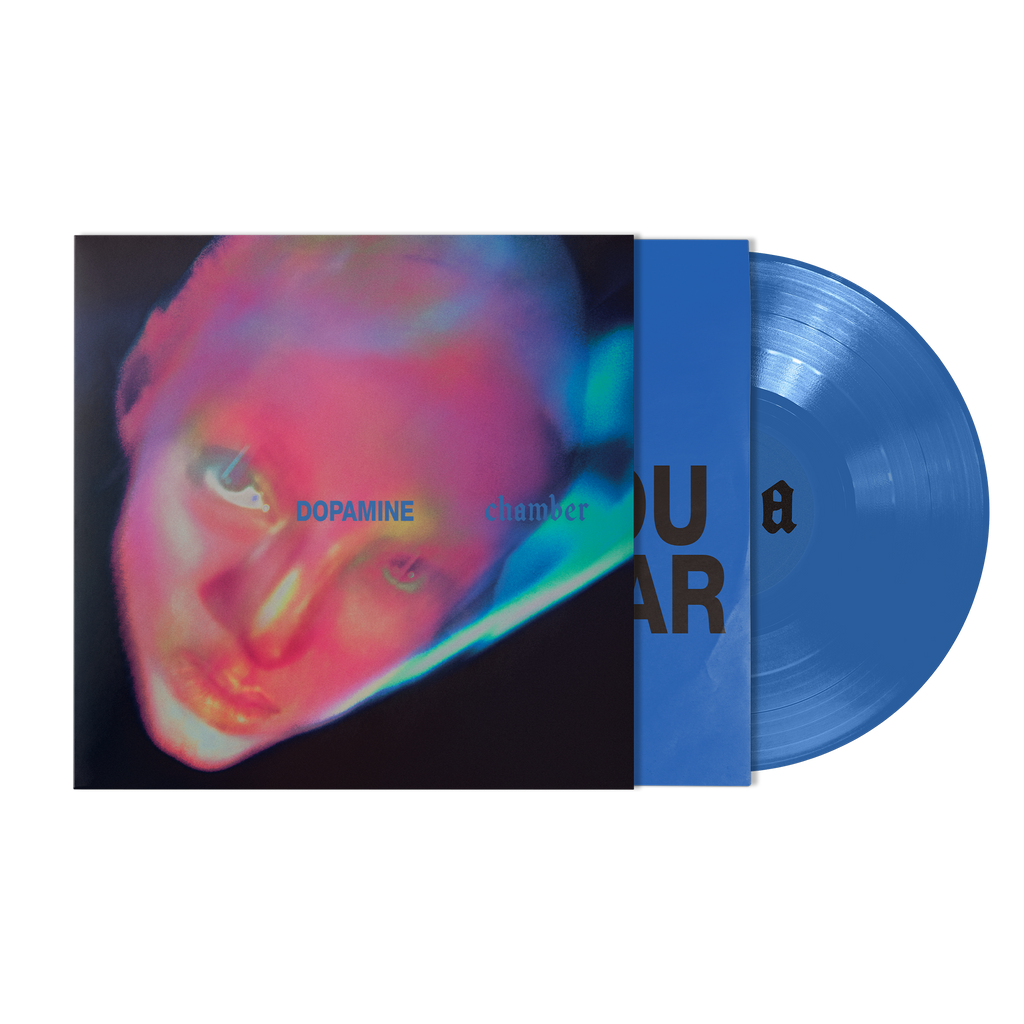 A vinyl record partially pulled from its sleeve, showing a blue disc and matching blue inner sleeve over an album cover with a neon portrait. 